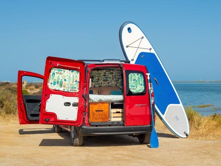 Mini campervan parked on the beach with a paddleboard in the Algarve, Portugal