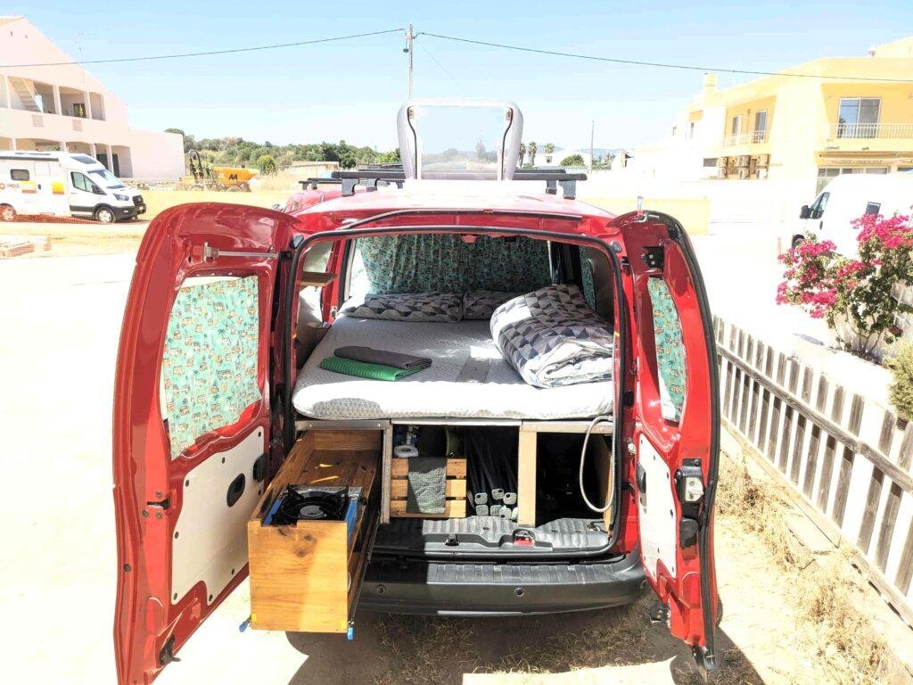 Rear doors open showing the bed and pull-out kitchen drawers